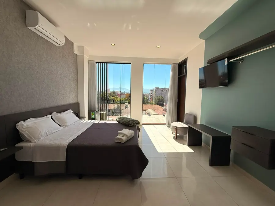 Monoambiente con cama y puertas abiertas al balcón