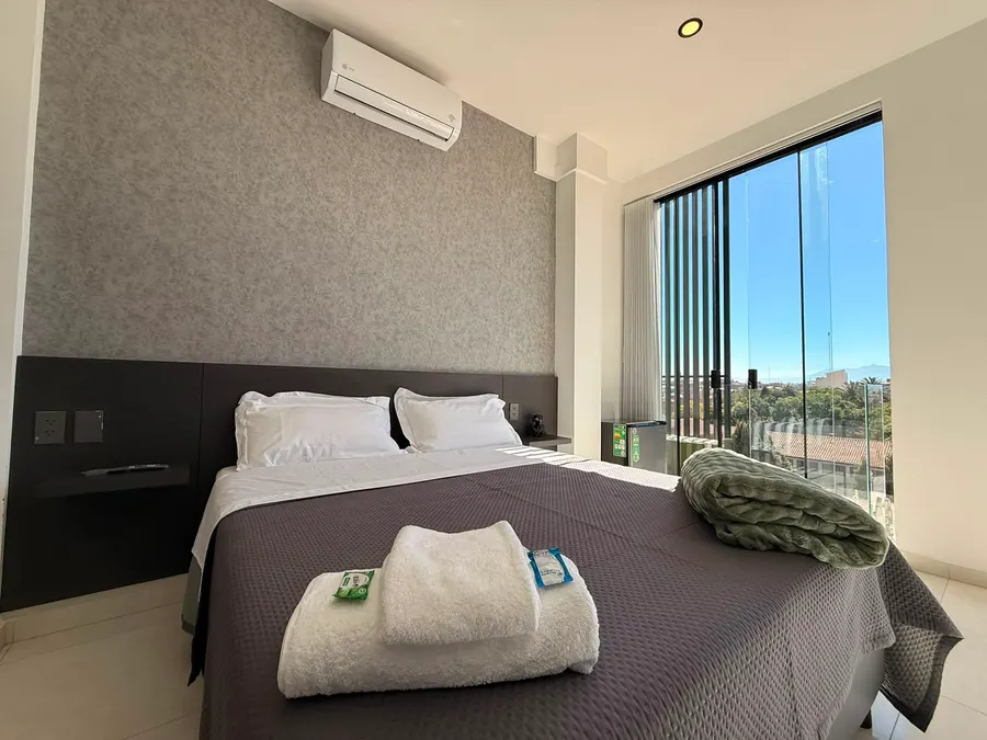 Cama junto al ventanal con vista a la ciudad